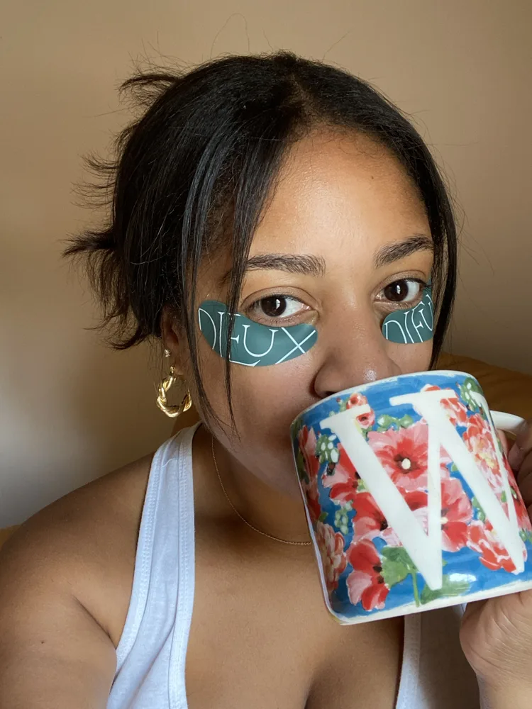 Whitney in under-eye patches sipping from a W mug